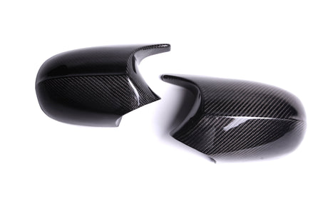 Two black carbon fiber car mirror covers are positioned against a white background, highlighting their glossy texture and sleek design.