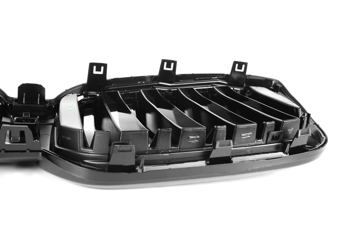 A black car grille features vertical slats and attachment clips, positioned on a plain white background, emphasizing its structure and design details.
