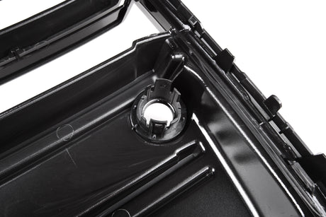 A glossy black plastic automotive part with a circular mount and ridges is shown in close-up, likely part of a larger engine or mechanical assembly.