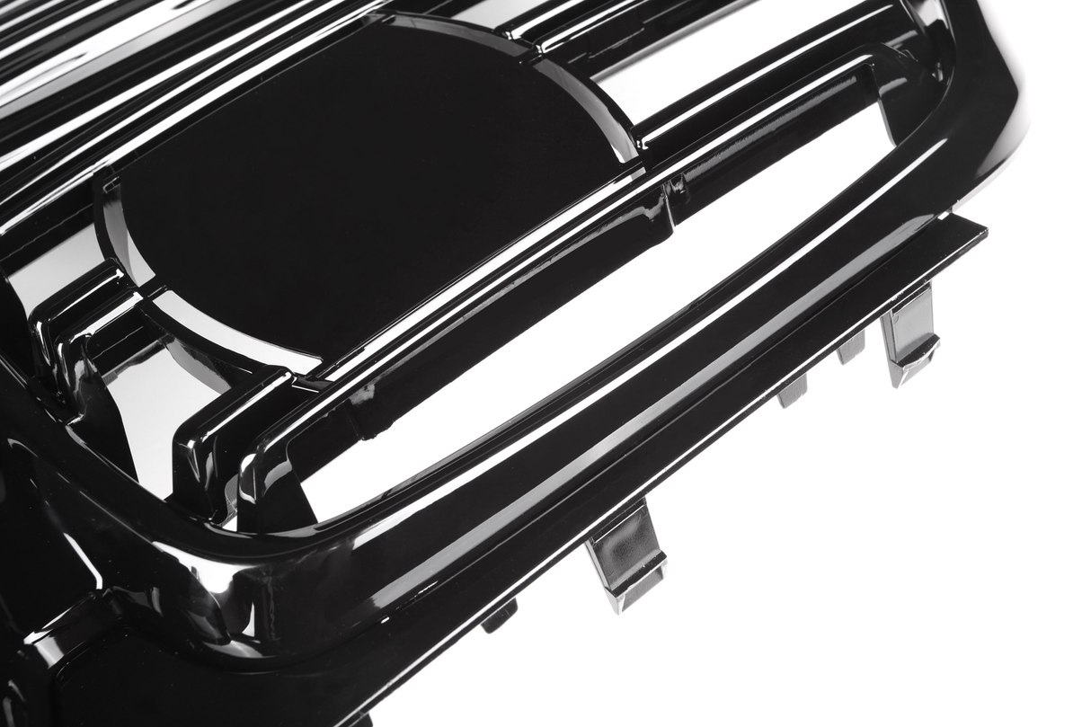 A shiny, black car grille with horizontal slats is positioned at an angle, possibly for a vehicle's front. It is isolated against a white background.