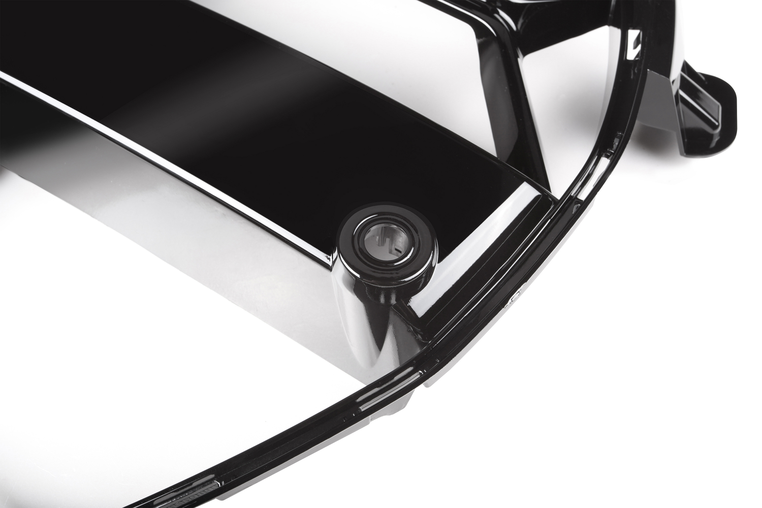 A black, glossy plastic cover with a circular keyhole, set on a white background, possibly part of a car accessory or appliance.