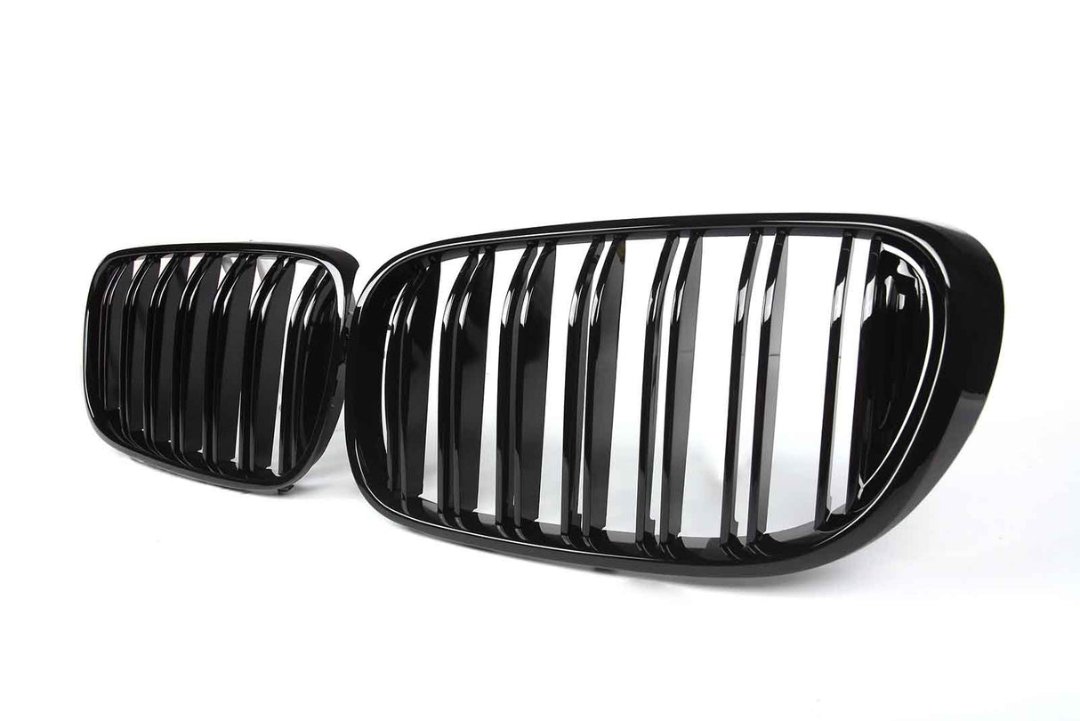 Two glossy black car grilles with vertical slats are displayed against a plain white background. The design suggests modern automotive styling.