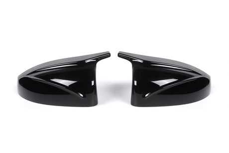 Two sleek black car side mirror covers face each other, reflecting light. They rest on a plain white background, showcasing their glossy finish and aerodynamic design.