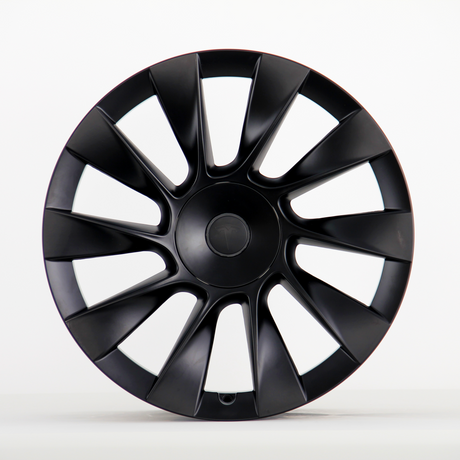 A black, multi-spoke car wheel cover with a subtle central logo sits upright against a plain white background, showcasing its sleek, aerodynamic design.