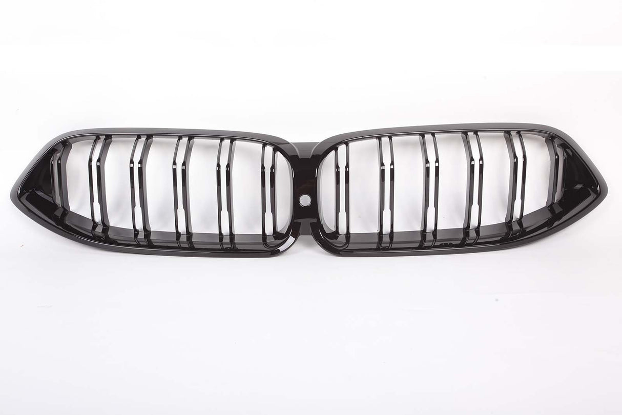 A glossy black car grille, featuring two connected oval sections with vertical slats, is placed on a plain white background.