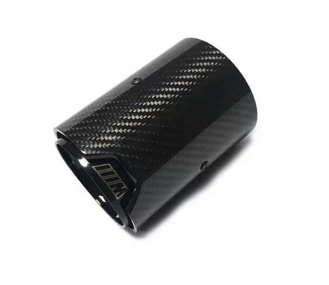 A carbon fiber exhaust tip lies angled on a white background, featuring a glossy checkered pattern with the letter "M" visible near the opening.