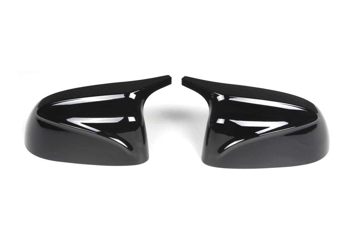 Two glossy black car side mirror covers are positioned symmetrically, facing each other on a plain white background. Their sleek, aerodynamic design reflects light.