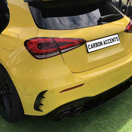 Yellow car parked on grass, featuring tinted windows and sleek tail lights. The license plate reads "CARBON ACCENTS." The car has a sporty design with dual exhausts.