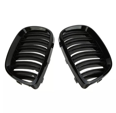 Two black, glossy car grilles with parallel slats are positioned side by side against a plain, white background, likely intended for vehicle front-end installation.