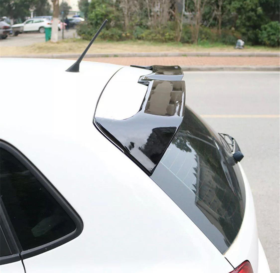 A car with a black rear spoiler is parked on a street. Its antenna is visible on the roof, and trees are in the background, suggesting an urban suburban setting.