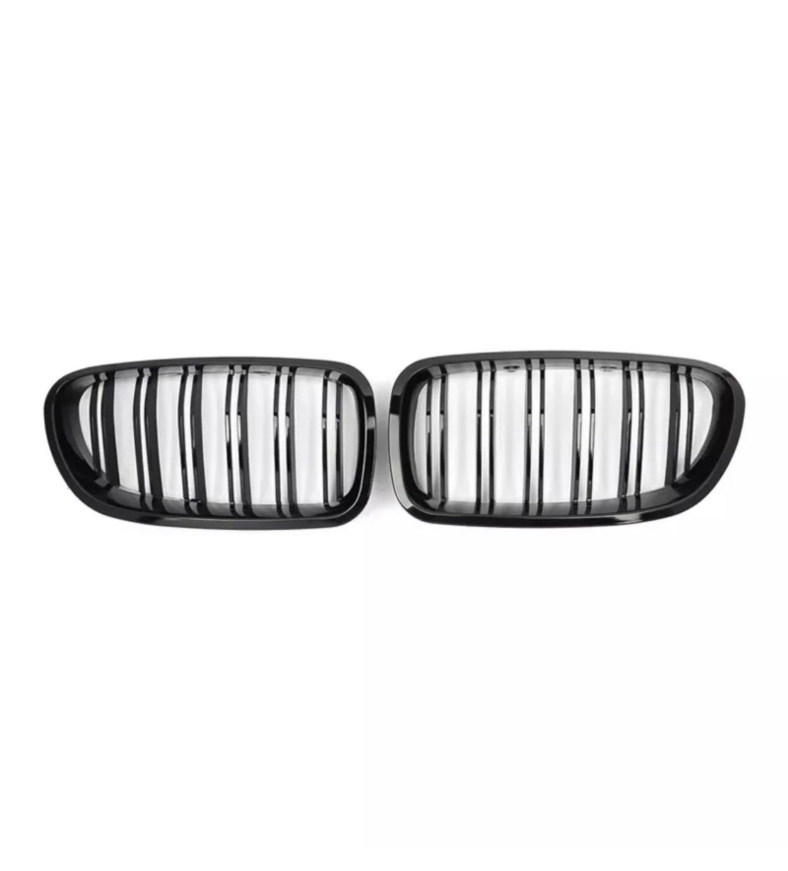 Two black, oval car grilles with vertical slats are positioned side by side against a plain white background.
