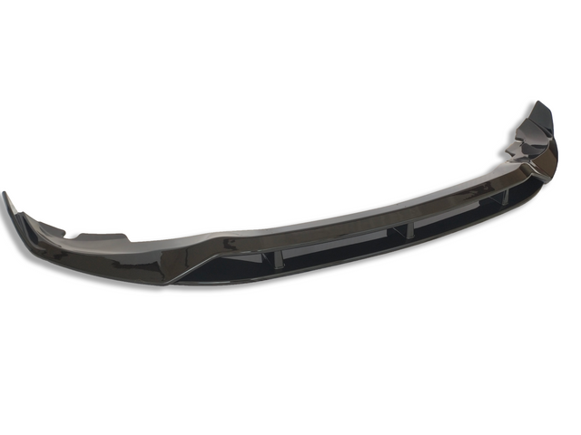 A glossy black car bumper lip sits isolated against a white background, showcasing its curved aerodynamic design and reflective surface.