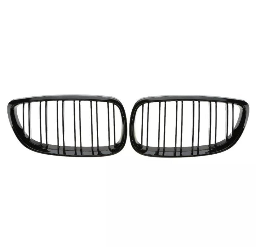Two black car grille inserts with vertical slats are placed side by side against a plain white background, suggesting a symmetrical design typical of vehicle front ends.