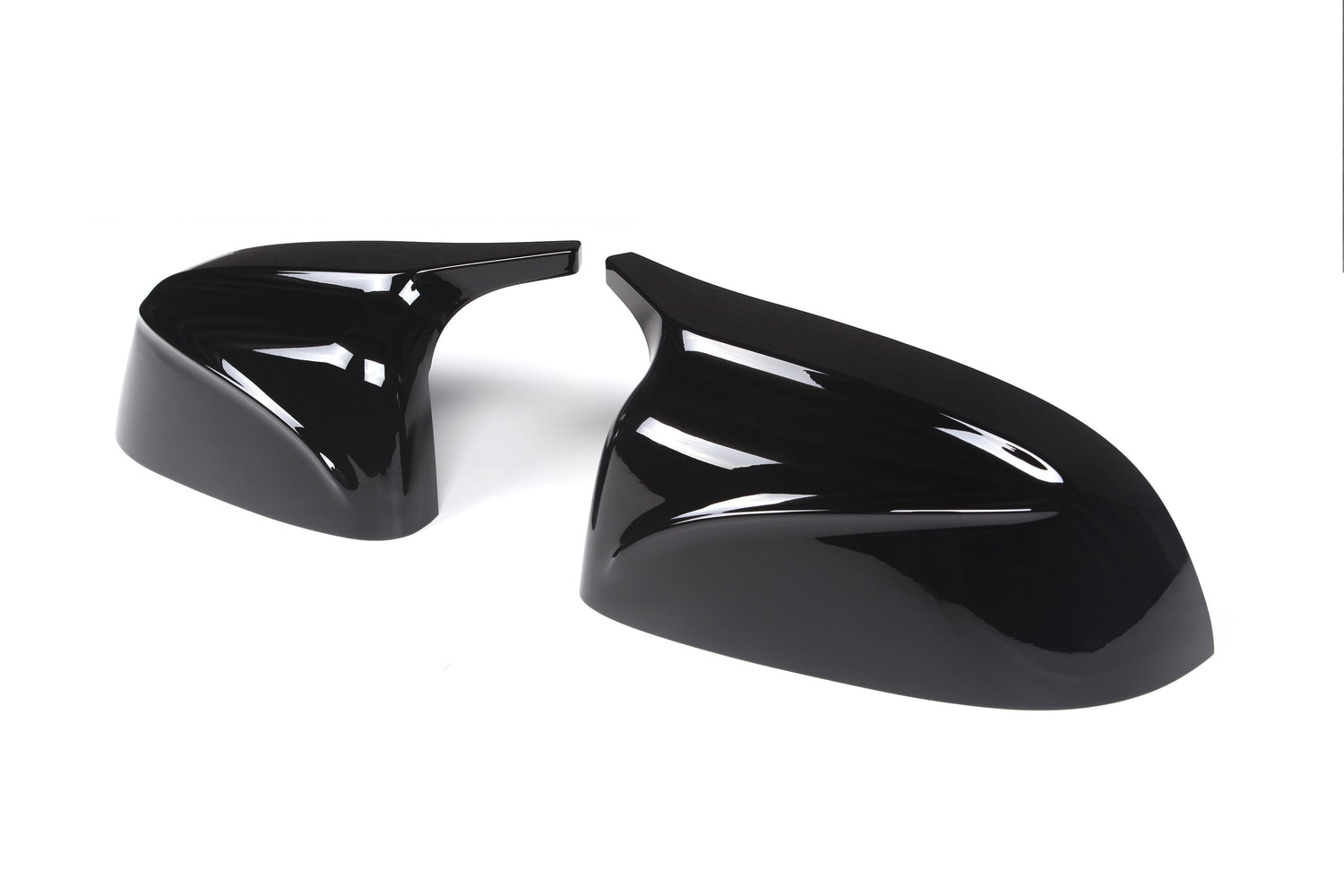 Glossy black car mirror covers resting on a plain white background, displaying sleek, aerodynamic curves and smooth surfaces.