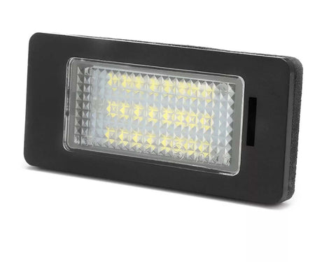 Rectangular LED light is shown, illuminated with multiple small yellow bulbs, encased in a textured clear cover. It's set in a black frame, likely suitable for automotive use.
