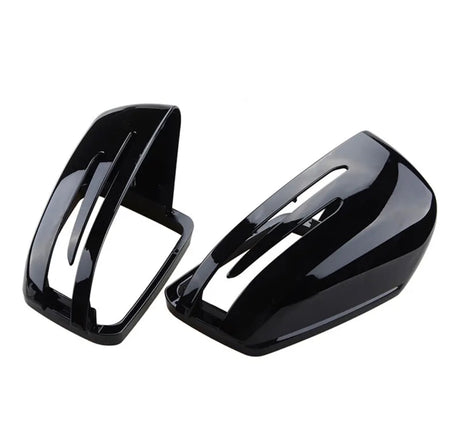 Two glossy black car mirror covers with sleek, aerodynamic slits are placed side by side against a plain white background.