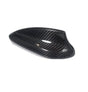 A carbon fiber car mirror cover, featuring a glossy, black textured surface, rests against a plain white background, highlighting its sleek design and curved aerodynamic shape.