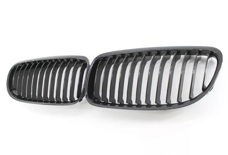 Two black car grille inserts with vertical slats lie side by side on a white background, resembling classic automotive front grille designs.