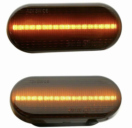 Two oval amber LED lights, one above the other, glow with horizontal strips of light. Both have inscriptions: "12V 5W E6" on the top left and "SM1 00 (E4) 23076" on the bottom.