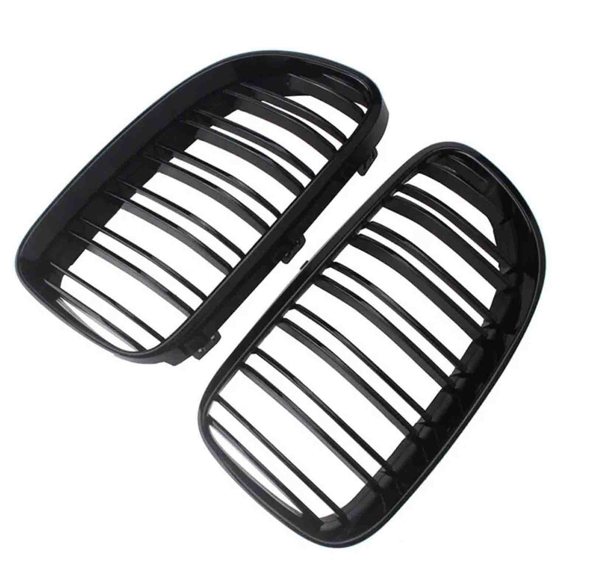 Two black car grille inserts, featuring vertical slats, lie angled against a white background. They are separated, showing both the front and back view of each grille.