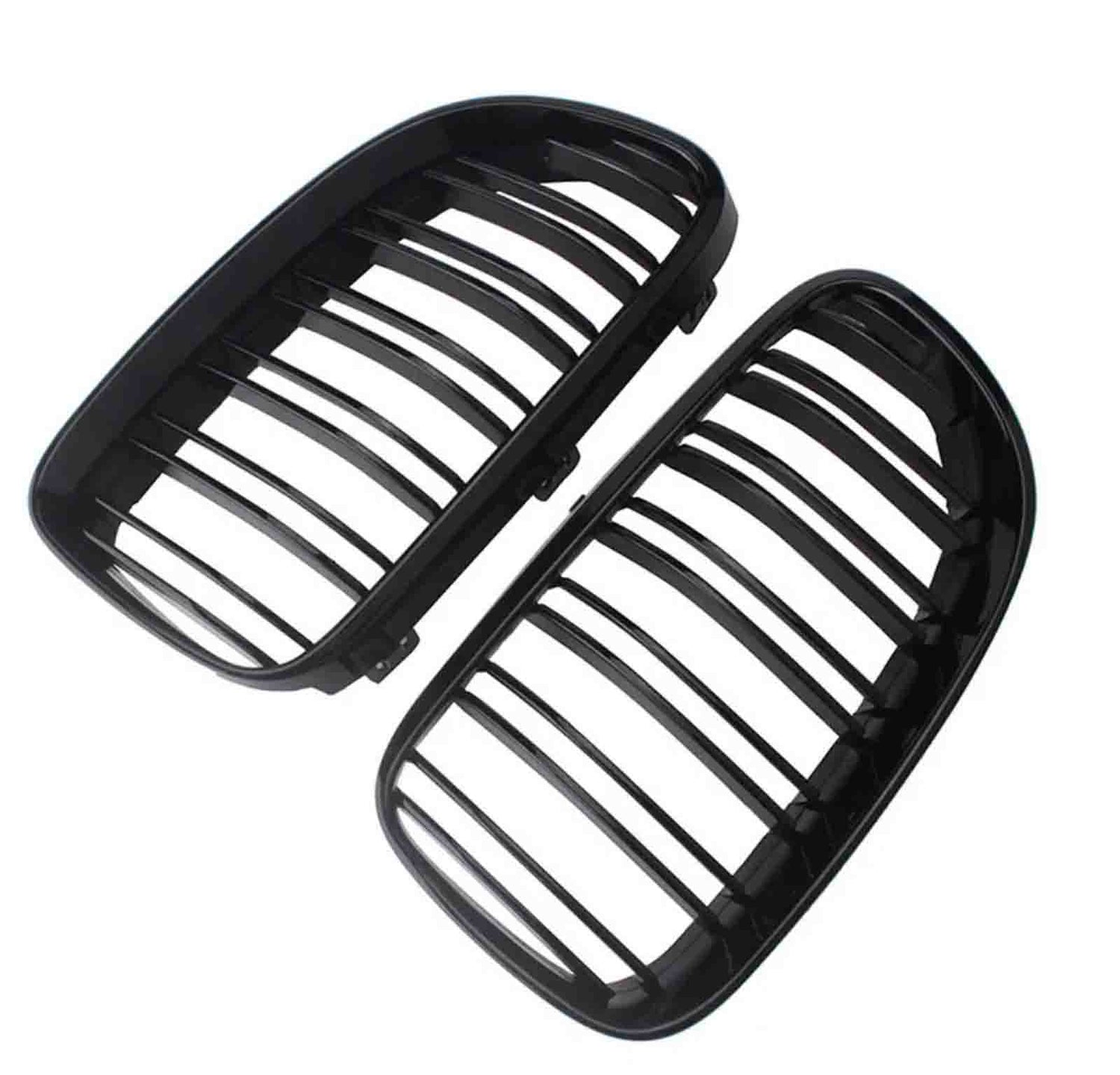 Two black car grille inserts, featuring vertical slats, lie angled against a white background. They are separated, showing both the front and back view of each grille.