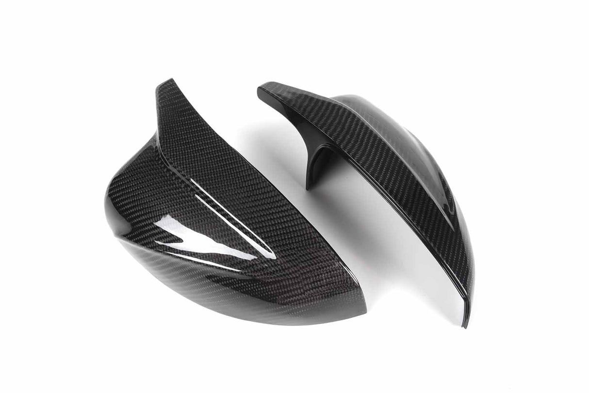 Two glossy carbon fiber mirror covers are displayed on a white background, highlighting their sleek, aerodynamic design and texture.