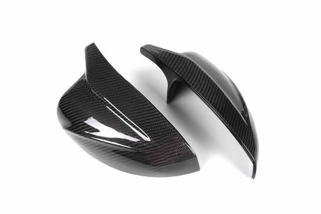 Two glossy carbon fiber mirror covers are displayed on a white background, highlighting their sleek, aerodynamic design and texture.