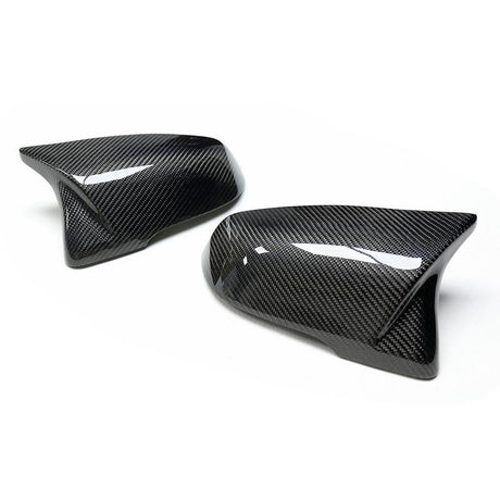 Two glossy carbon fiber car mirror covers are displayed, positioned against a plain white background, highlighting their sleek design and texture.
