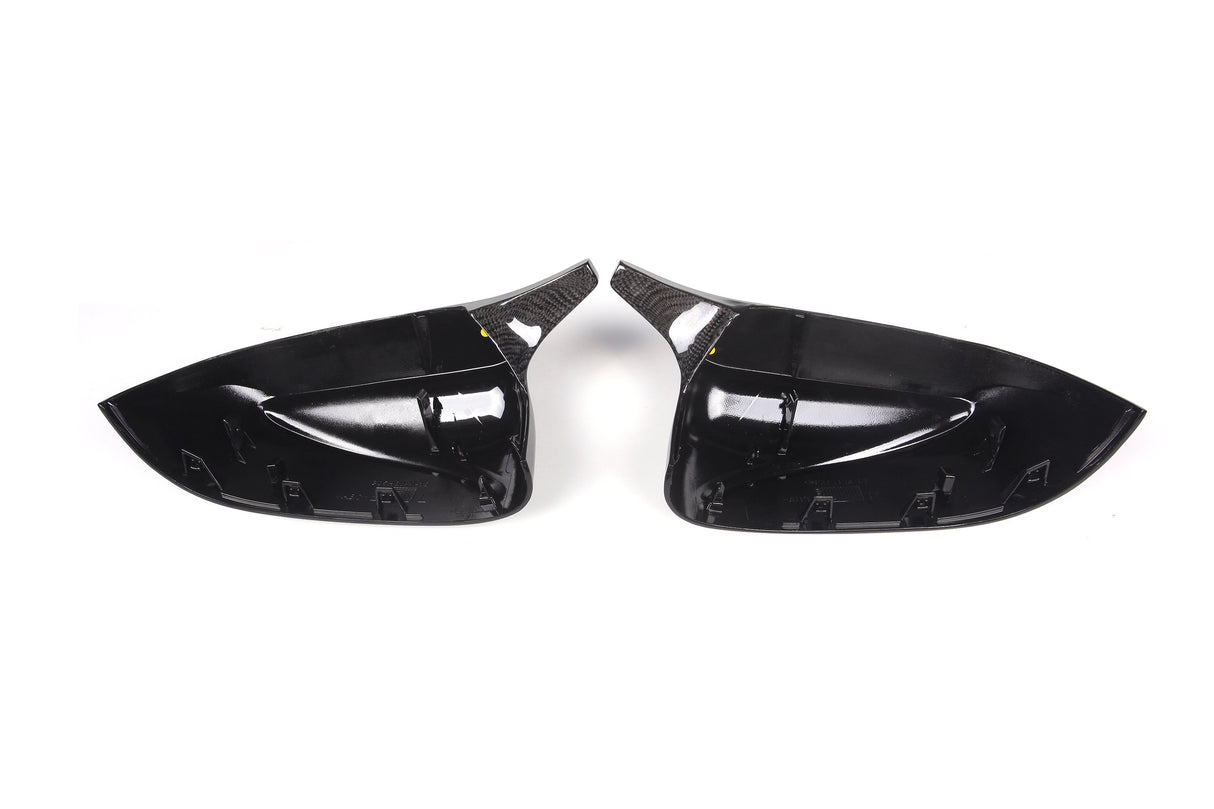 Two glossy black car side mirror covers with a carbon fiber texture are placed side by side on a plain white background.