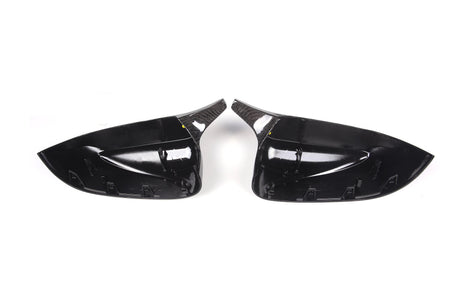 Two glossy black car side mirror covers with a carbon fiber texture are placed side by side on a plain white background.