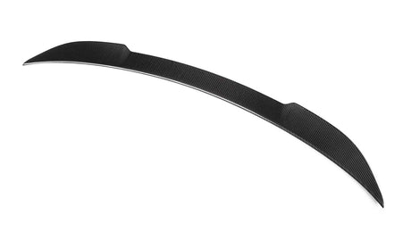 A carbon fiber car spoiler features a sleek, curved design, resting against a plain white background.