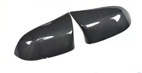 Carbon fiber car mirror covers, positioned side by side, displaying a glossy surface with visible texture, set against a plain white background.