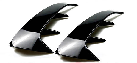 Two sleek, black, curved automotive fins with angular protrusions are positioned side by side on a plain white background, emphasizing their glossy finish and aerodynamic design.