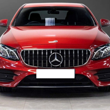 A red Mercedes-Benz car, viewed from the front, with prominent grille and headlights. It's parked indoors on a tiled floor, with a blurred background. No text visible.