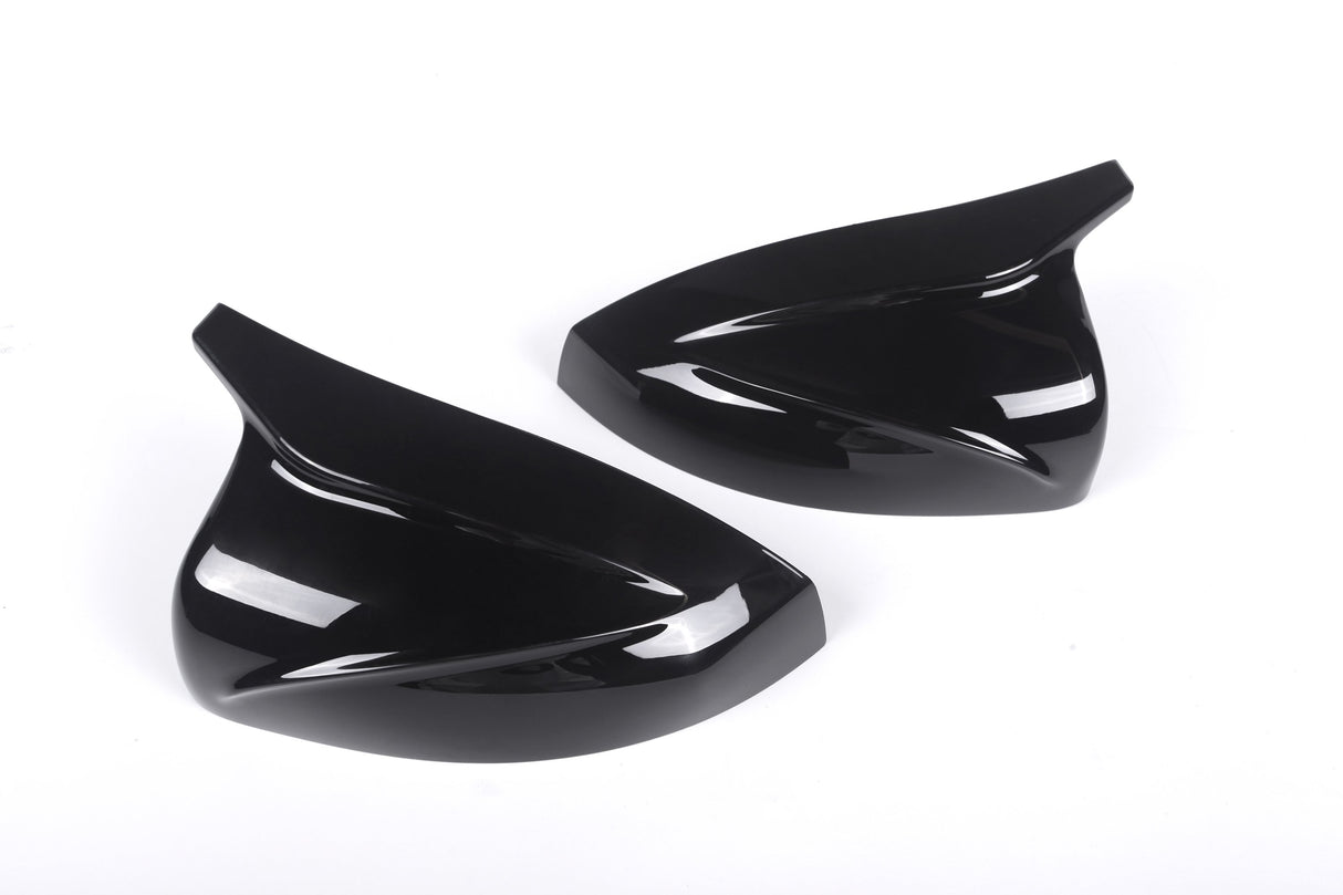 Two sleek, black, aerodynamic car mirror covers lay side by side on a plain white background, emphasizing their glossy finish and curved design.