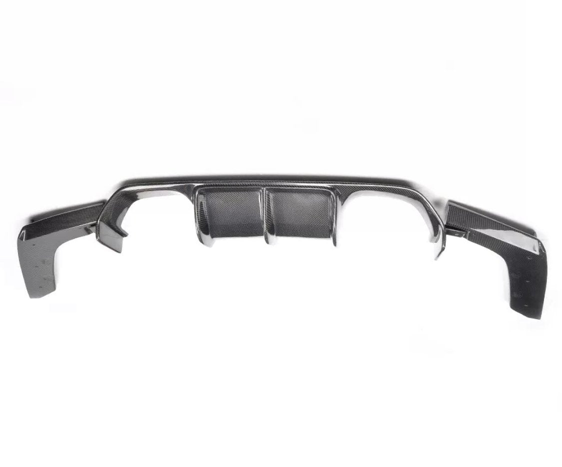 A black carbon fiber diffuser with aerodynamic fins is displayed against a plain white background. It has a sleek, curved design and is intended for use on a vehicle's rear bumper.