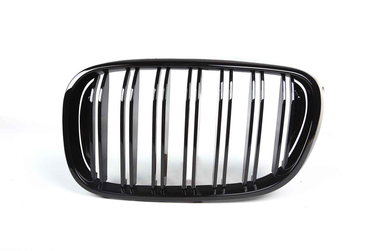 A shiny black car grille features vertical slats framed by an oval shape, set against a plain white background.