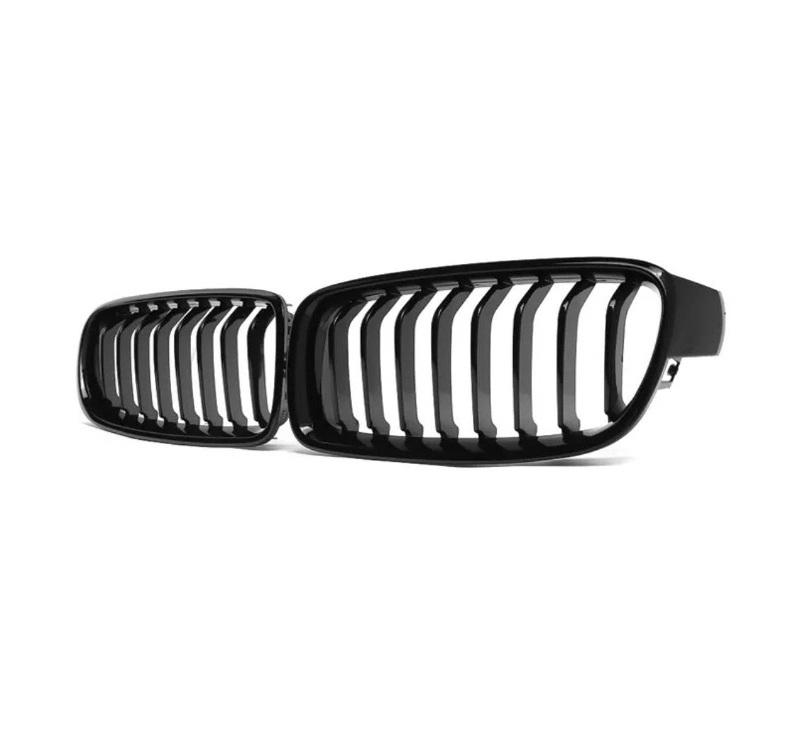 Black car grille with vertical slats, positioned angled toward each other, resting against a plain white background.