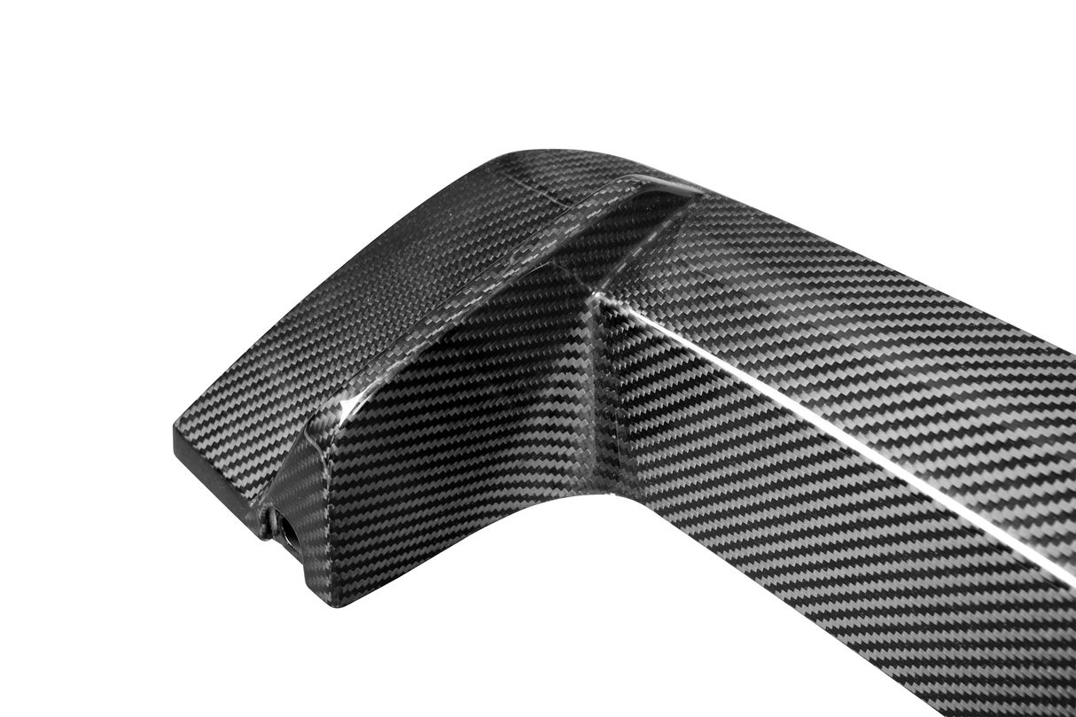 A carbon fiber car part, featuring a sleek, curved design with a glossy finish, lies against a plain white background.