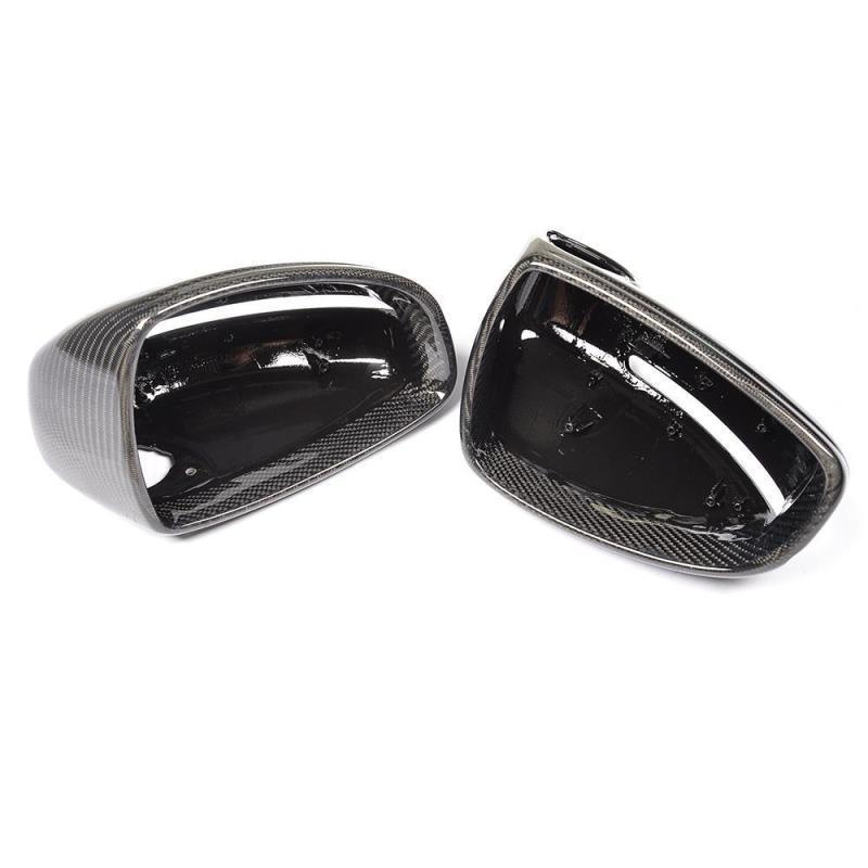 Two glossy black carbon fiber side mirror covers rest side by side, displaying their smooth, reflective surfaces against a plain white background.