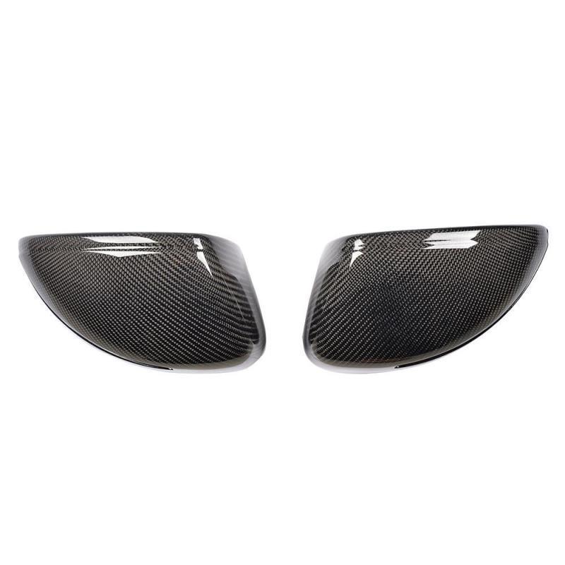 Two carbon fiber wing mirror covers are side by side, angled towards each other, against a plain white background. The covers have a glossy finish with a detailed woven pattern.