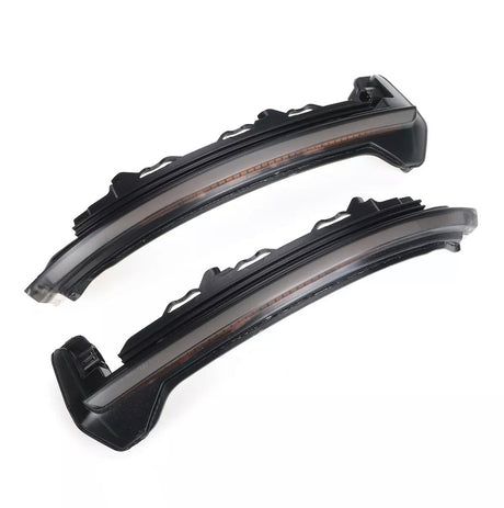 Two sleek black curved LED car lights with translucent covers lie side by side on a white background, showcasing their modern design intended for automotive use.
