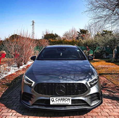 A gray car is parked on a brick driveway, surrounded by winter trees and dry grass. Text reads: "CARBON ACCENTS" and “WWW.CARBONACCENTS.CO.UK.”