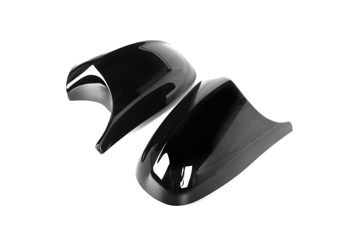 Two glossy black plastic covers lay side by side, displaying curved, aerodynamic designs, against a plain white background.