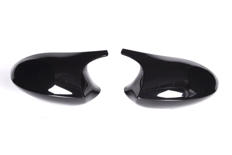 Two glossy black mirror covers face each other on a plain white background, showcasing their curved, sleek design ideal for vehicle customization.