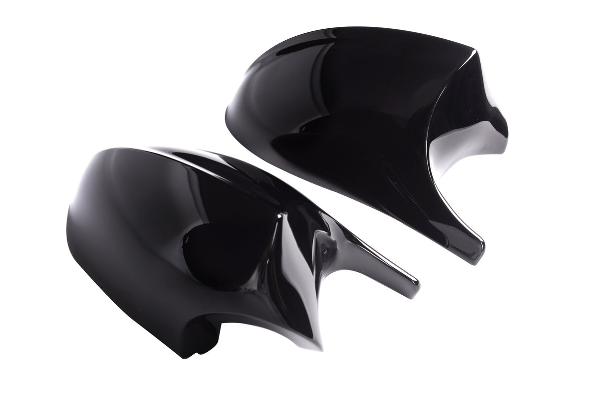 Two shiny black car mirror covers rest side by side against a plain white background, reflecting light on their smooth surfaces.