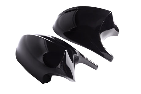 Two shiny black car mirror covers rest side by side against a plain white background, reflecting light on their smooth surfaces.