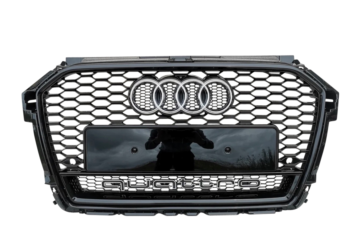 A car grille features a honeycomb pattern, with the Audi logo and the word "quattro" prominently displayed on a metallic surface, set against a gray background.