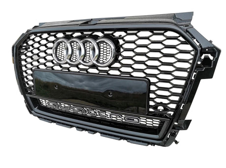 A black hexagonal car grille featuring the Audi logo and the word "quattro" at the bottom, displayed against a plain white background.