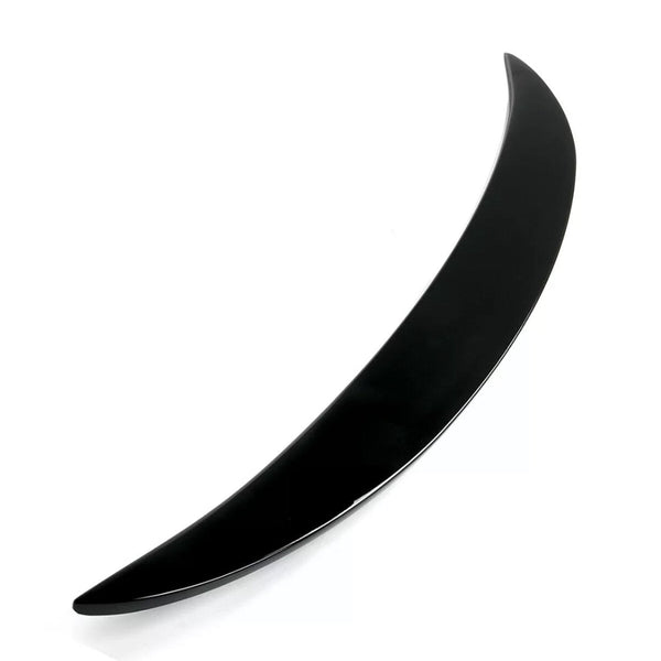 A sleek, curved black object, resembling a thin crescent, lies on a white surface. The object is glossy and tapers to a point at both ends.